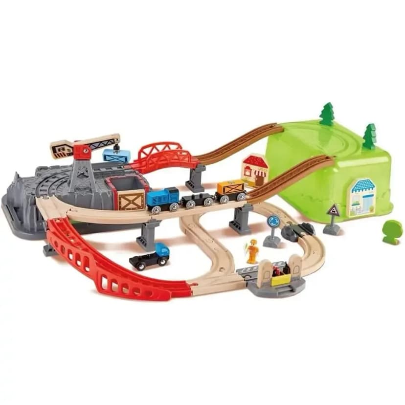 Assembled railway layout with a red crane, a grey mountain, red bridges, looping track, a small train with carriages, trees, small buildings and a green storage box.