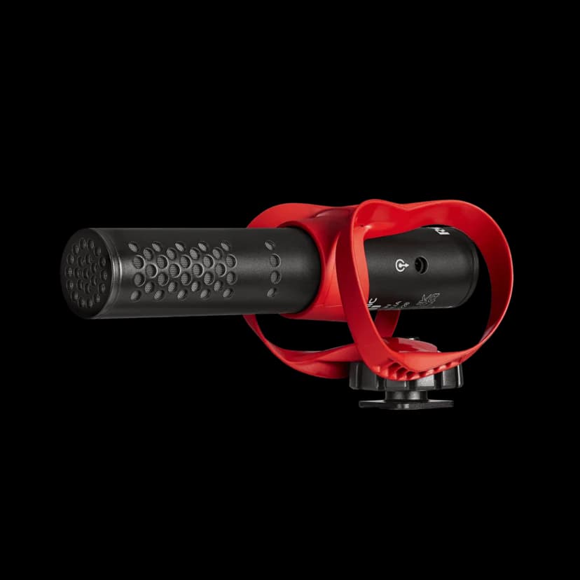 Black cylindrical shotgun microphone held in a red isolation mount with a cold shoe base, on a white background